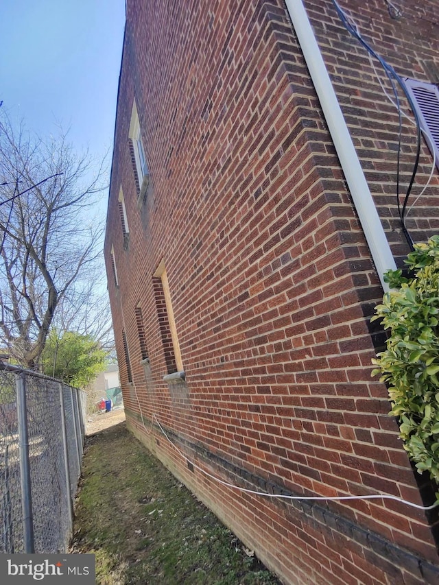 view of home's exterior featuring brick siding and fence