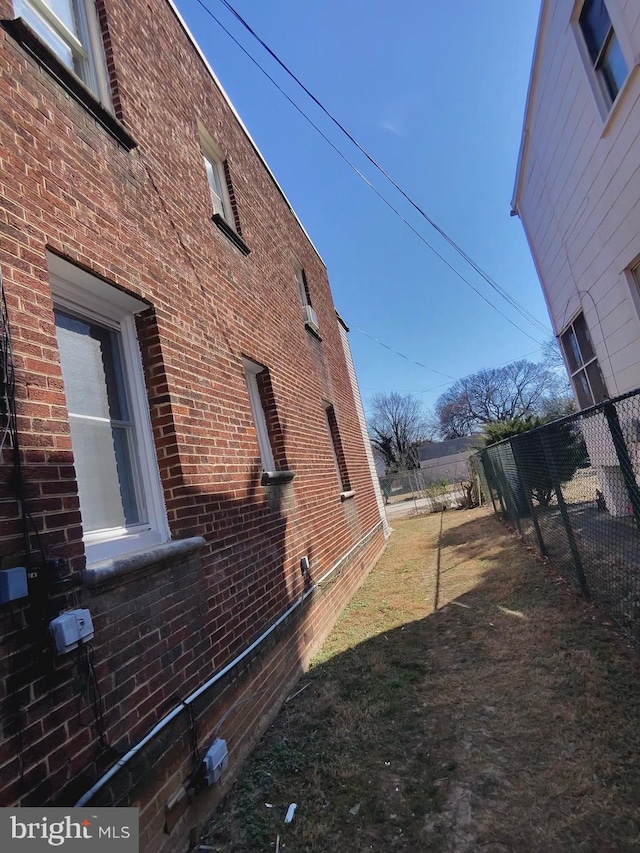 view of home's exterior with fence, brick siding, and a lawn