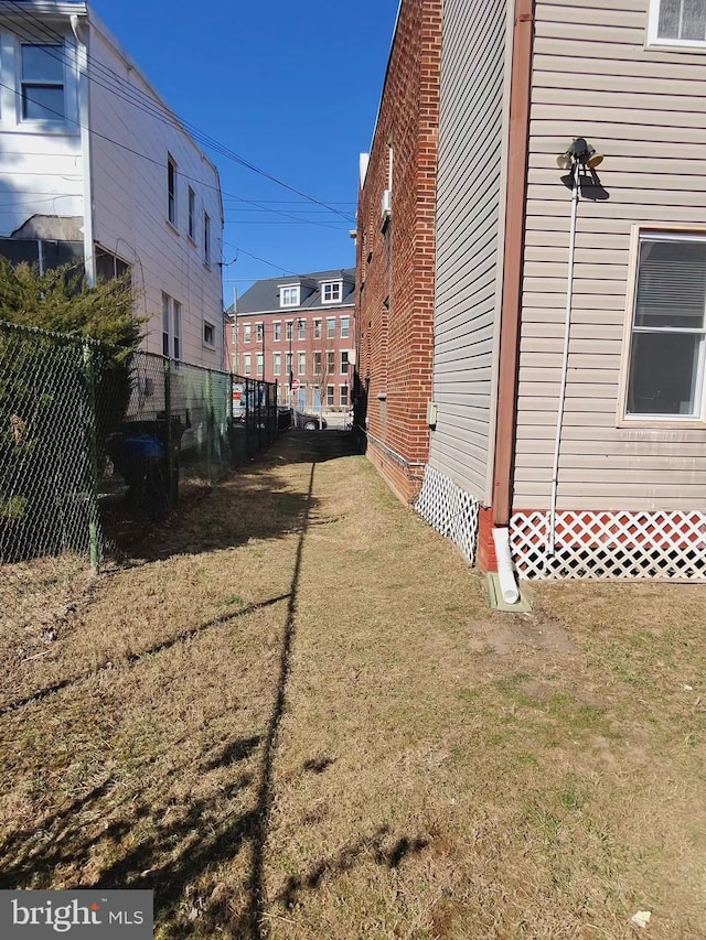 view of side of property featuring fence and a lawn