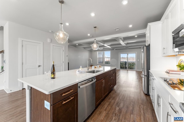 kitchen with a sink, coffered ceiling, open floor plan, dark wood finished floors, and appliances with stainless steel finishes