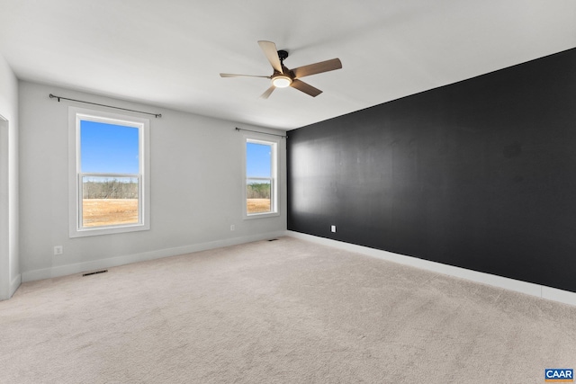 carpeted empty room with visible vents, baseboards, and a ceiling fan