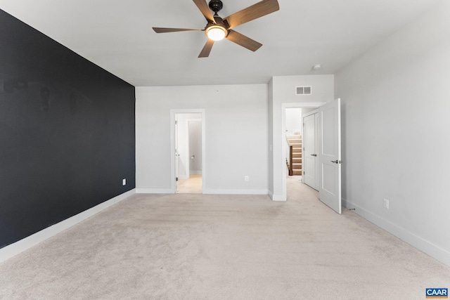 unfurnished bedroom featuring visible vents, light colored carpet, baseboards, and ceiling fan