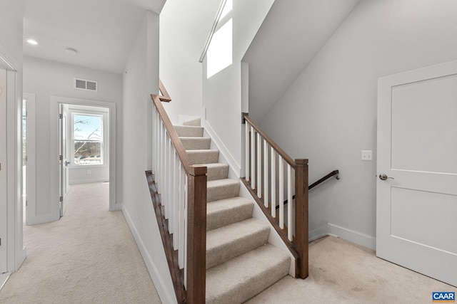 stairway featuring visible vents, a skylight, baseboards, and carpet floors