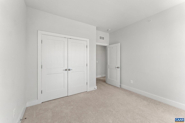 unfurnished bedroom with carpet flooring, baseboards, visible vents, and a closet