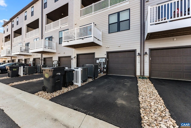 view of property featuring central AC unit, a garage, and driveway