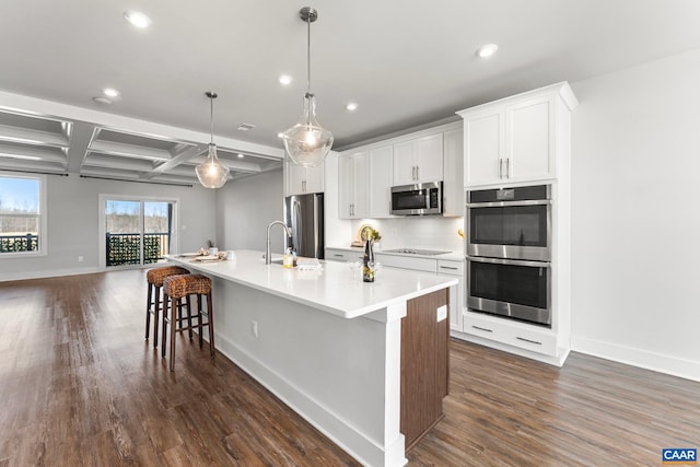 kitchen with backsplash, dark wood finished floors, recessed lighting, appliances with stainless steel finishes, and a large island with sink