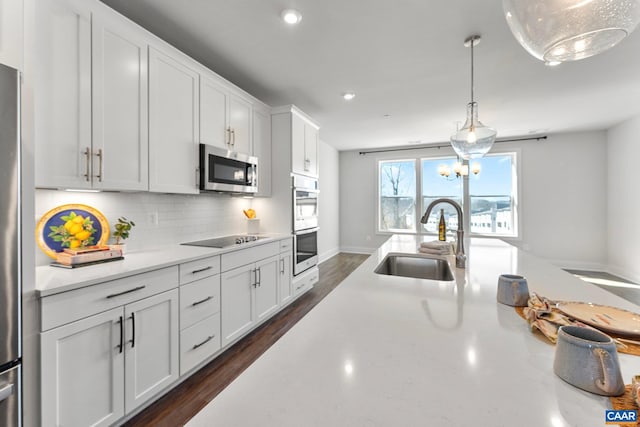 kitchen featuring dark wood finished floors, a sink, decorative backsplash, white cabinets, and appliances with stainless steel finishes