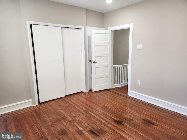 unfurnished bedroom featuring a closet, baseboards, and wood finished floors