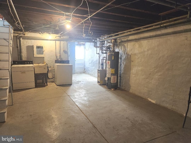 unfinished below grade area featuring water heater, a sink, and separate washer and dryer