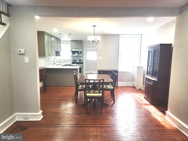 dining space featuring dark wood-style floors, a notable chandelier, and baseboards