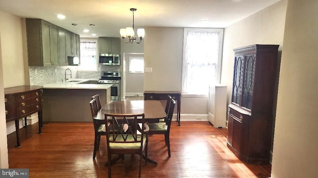 dining space featuring dark wood finished floors, a notable chandelier, and baseboards