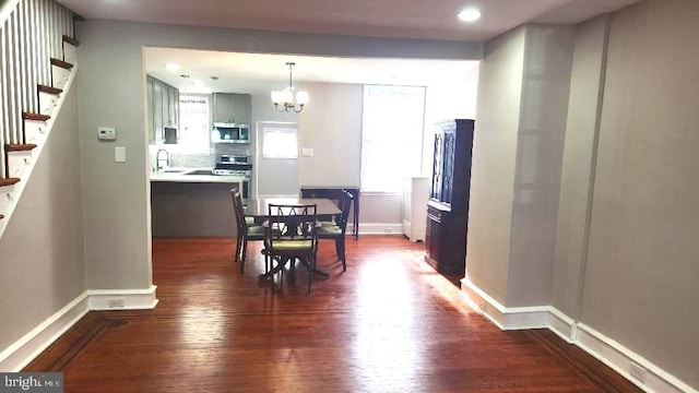 dining room featuring an inviting chandelier, dark wood-type flooring, stairway, and baseboards