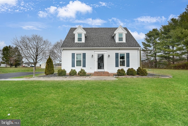 new england style home with a shingled roof and a front lawn