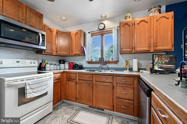 kitchen with brown cabinets, stainless steel appliances, light countertops, and a sink