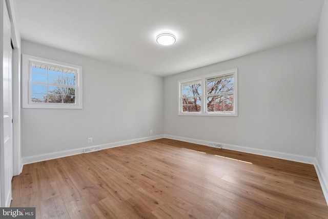 empty room featuring visible vents, baseboards, and wood-type flooring