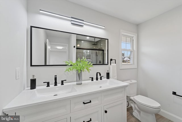 bathroom featuring toilet, wood finished floors, a stall shower, and a sink