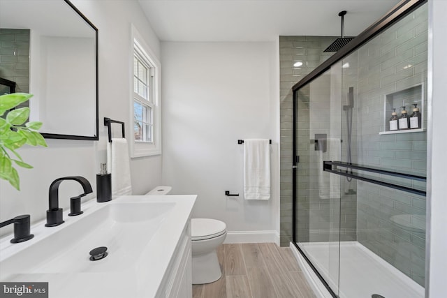 full bathroom with a shower stall, baseboards, toilet, wood finished floors, and vanity