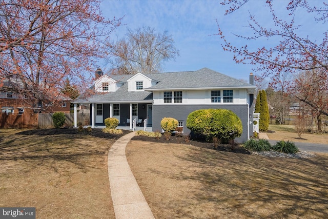 view of front of property featuring a front lawn, a porch, a chimney, and fence