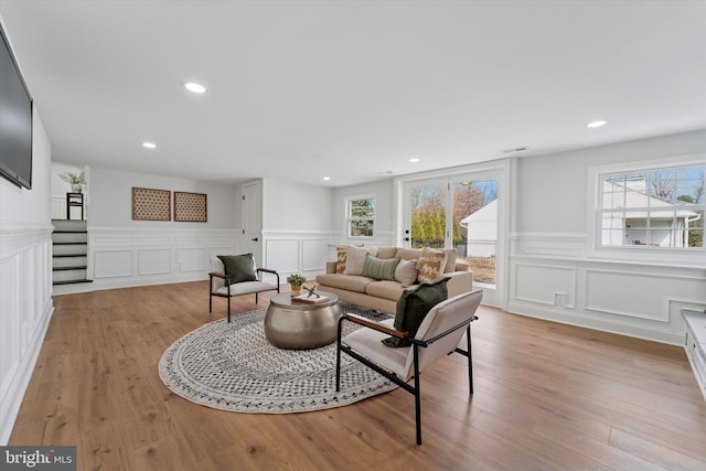 living room with recessed lighting, light wood-style floors, and a decorative wall