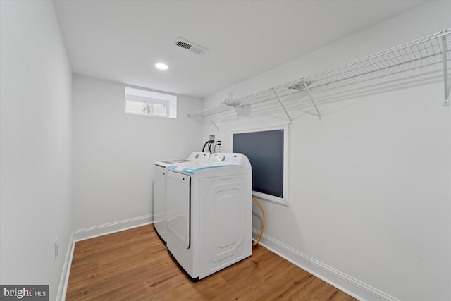 clothes washing area with laundry area, light wood-style floors, baseboards, and separate washer and dryer