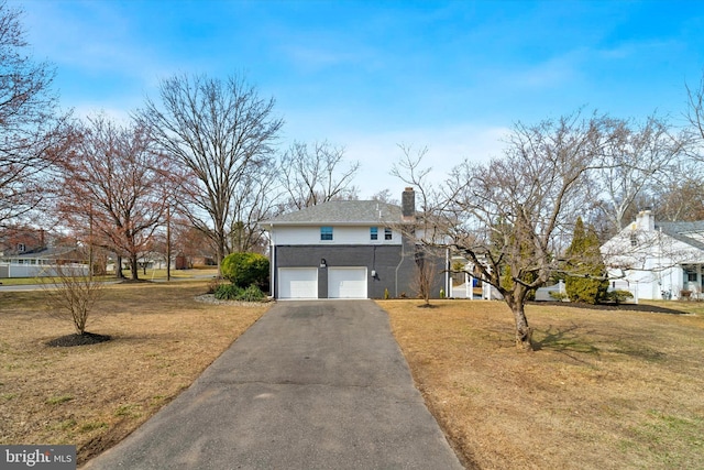 view of front facade with a front yard, a chimney, and aphalt driveway