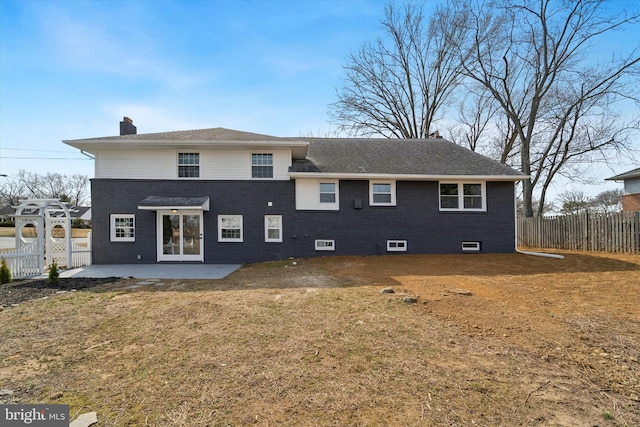 rear view of house with brick siding, a lawn, a chimney, a fenced backyard, and a patio area