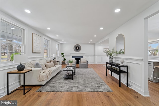 living area with a decorative wall, recessed lighting, a fireplace, and light wood-style floors