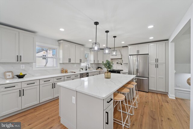 kitchen featuring stainless steel appliances, a kitchen breakfast bar, light wood-style flooring, and a center island