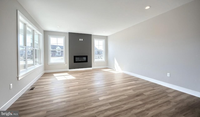 unfurnished living room with visible vents, wood finished floors, recessed lighting, a large fireplace, and baseboards