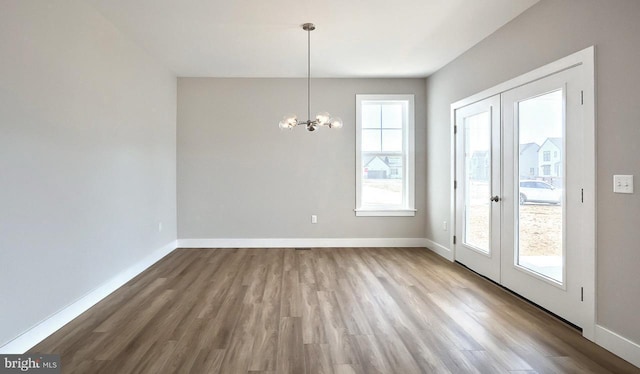 unfurnished dining area featuring french doors, baseboards, and wood finished floors