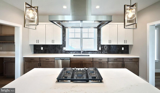 kitchen featuring backsplash, island exhaust hood, stainless steel appliances, white cabinetry, and a sink