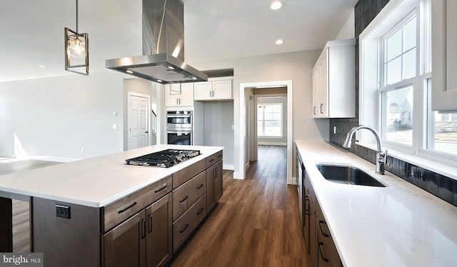 kitchen featuring island exhaust hood, a sink, backsplash, appliances with stainless steel finishes, and white cabinets