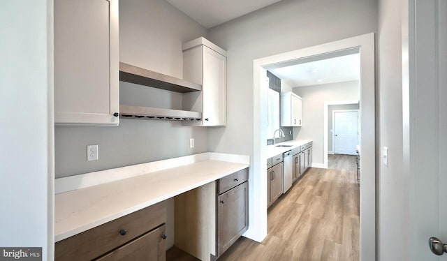 kitchen with open shelves, light wood-style flooring, built in desk, and white cabinetry