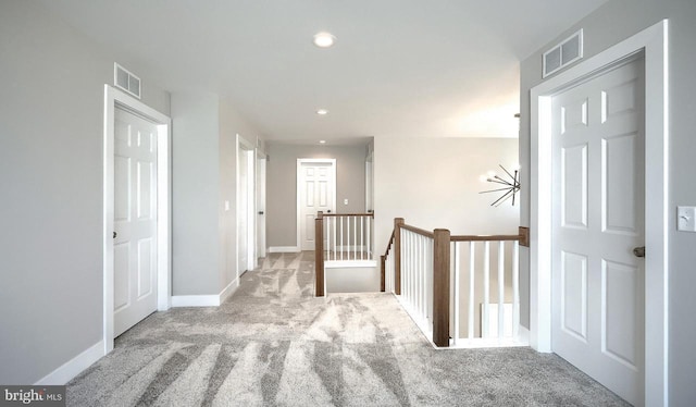 hallway with recessed lighting, visible vents, an upstairs landing, and carpet flooring