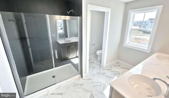 bathroom with baseboards, double vanity, a stall shower, marble finish floor, and a sink