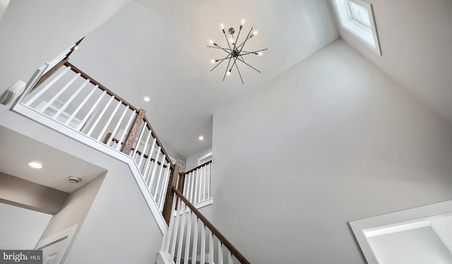 stairway with a high ceiling, a notable chandelier, and recessed lighting