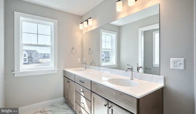 bathroom with a sink, baseboards, marble finish floor, and double vanity