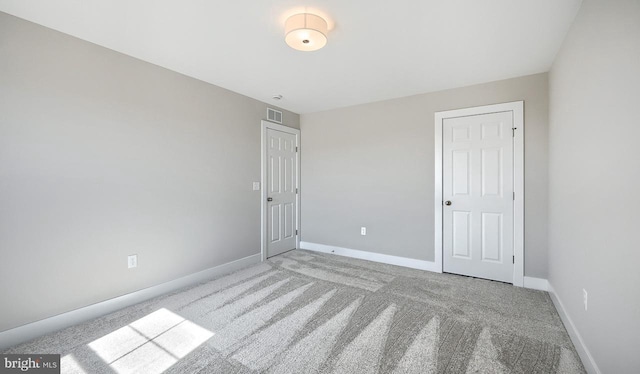 unfurnished bedroom with baseboards, visible vents, and light carpet