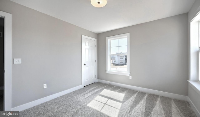 unfurnished room with baseboards and carpet