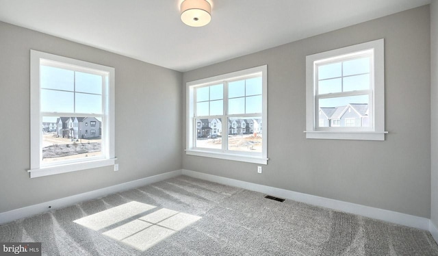 empty room featuring visible vents, carpet flooring, and baseboards