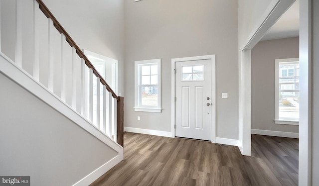 foyer entrance featuring stairway, a towering ceiling, baseboards, and wood finished floors