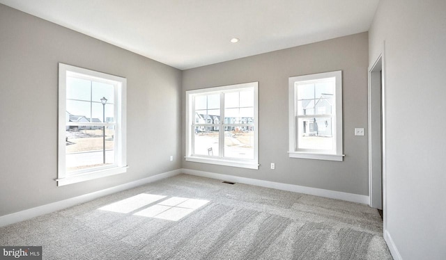 carpeted spare room with visible vents and baseboards