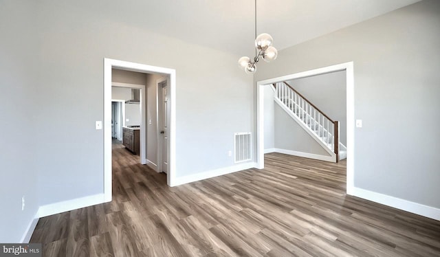 unfurnished dining area with visible vents, baseboards, stairs, an inviting chandelier, and wood finished floors