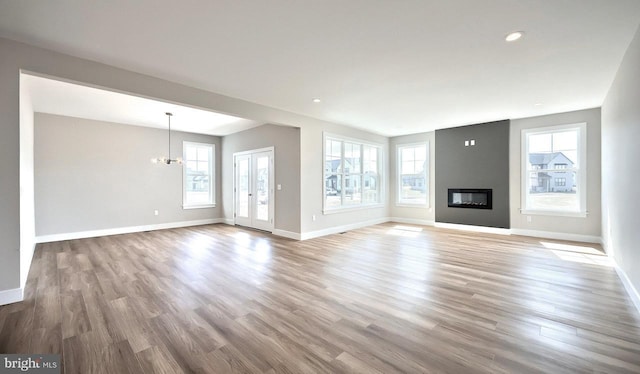 unfurnished living room featuring baseboards, a healthy amount of sunlight, wood finished floors, and a fireplace