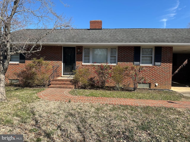 ranch-style home with a front lawn, brick siding, roof with shingles, and a chimney