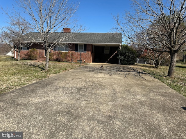 ranch-style home with brick siding, driveway, a chimney, and a front yard