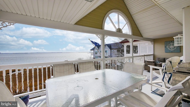 wooden terrace with outdoor dining area and a water view