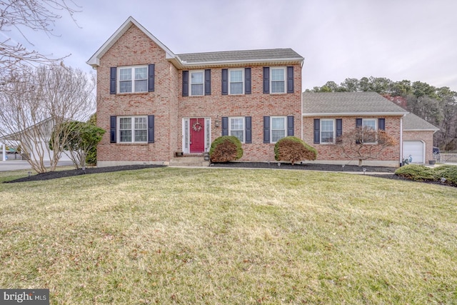 colonial house featuring brick siding, a front yard, and a shingled roof