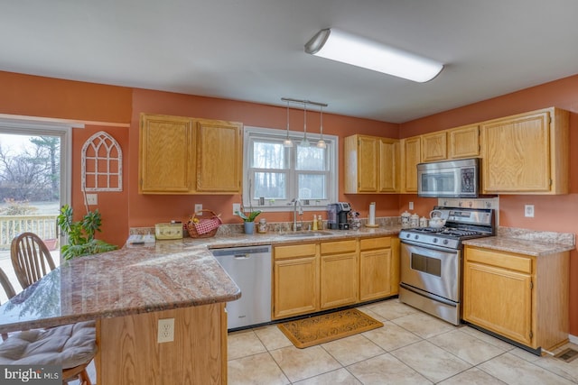 kitchen featuring a kitchen bar, light countertops, a peninsula, stainless steel appliances, and a sink