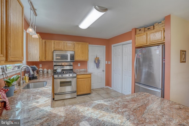 kitchen with light stone countertops, pendant lighting, light tile patterned floors, appliances with stainless steel finishes, and a sink